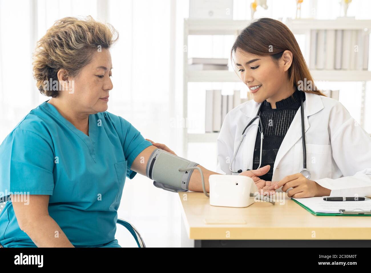 Female doctor measuring blood pressure of senior woman elderly at ...