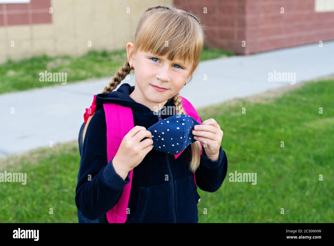 Young student caucasian girl holding protective cotton mask for school. Return back to school, reopening, new life. Stock Photo