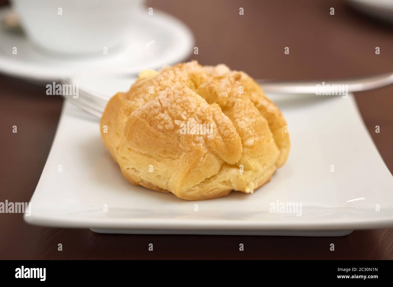 round baked eclair cake with cream on a white plate, selective focus Stock Photo