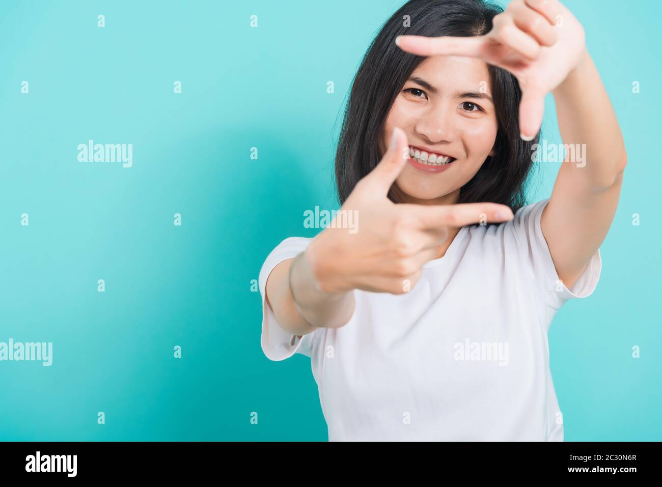 Portrait Asian beautiful happy young woman smile white teeth wear white t-shirt standing making creativity photography frame with hands and fingers, o Stock Photo