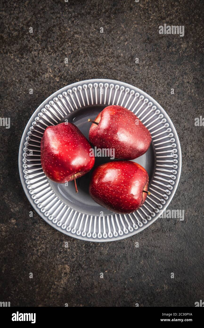 Three ripe red apples on plate. Top view. Stock Photo