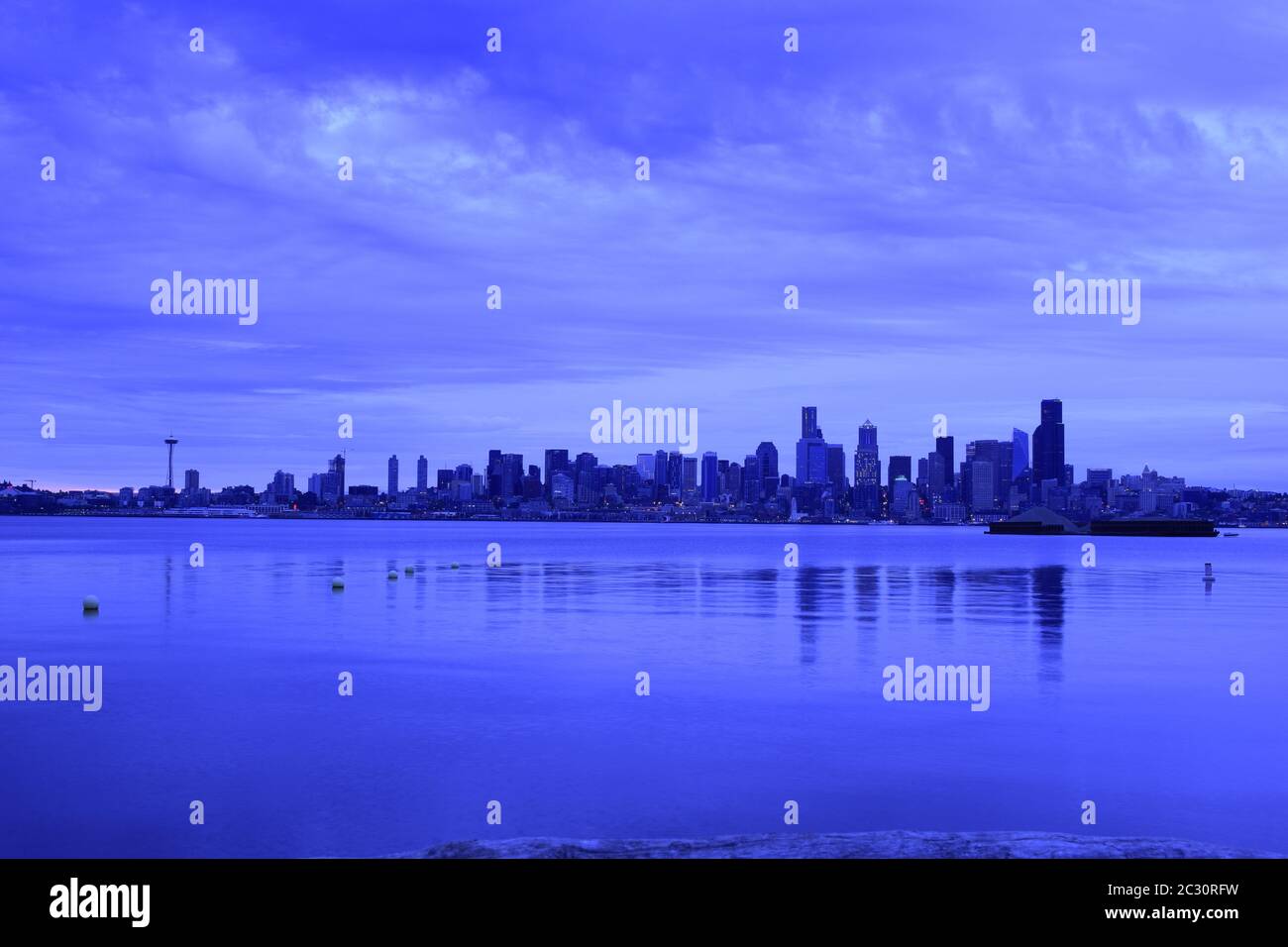 Iconic Seattle Skyline From Across The Puget Sound During A Dramatically Cloudy Dawn Stock Photo