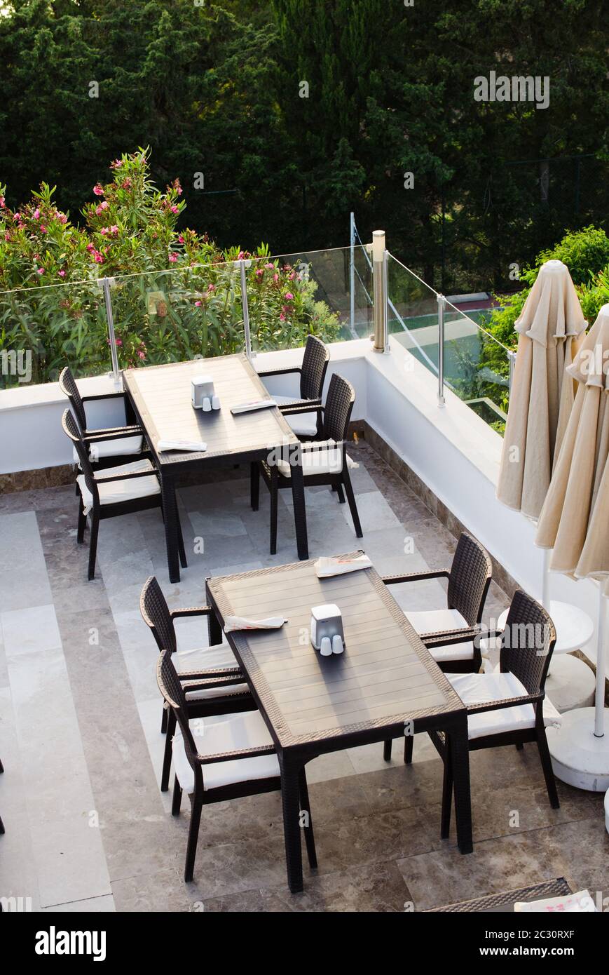 Wattled tables and chairs on terrace summer cafe overlooking the green park. Top view. Stock Photo