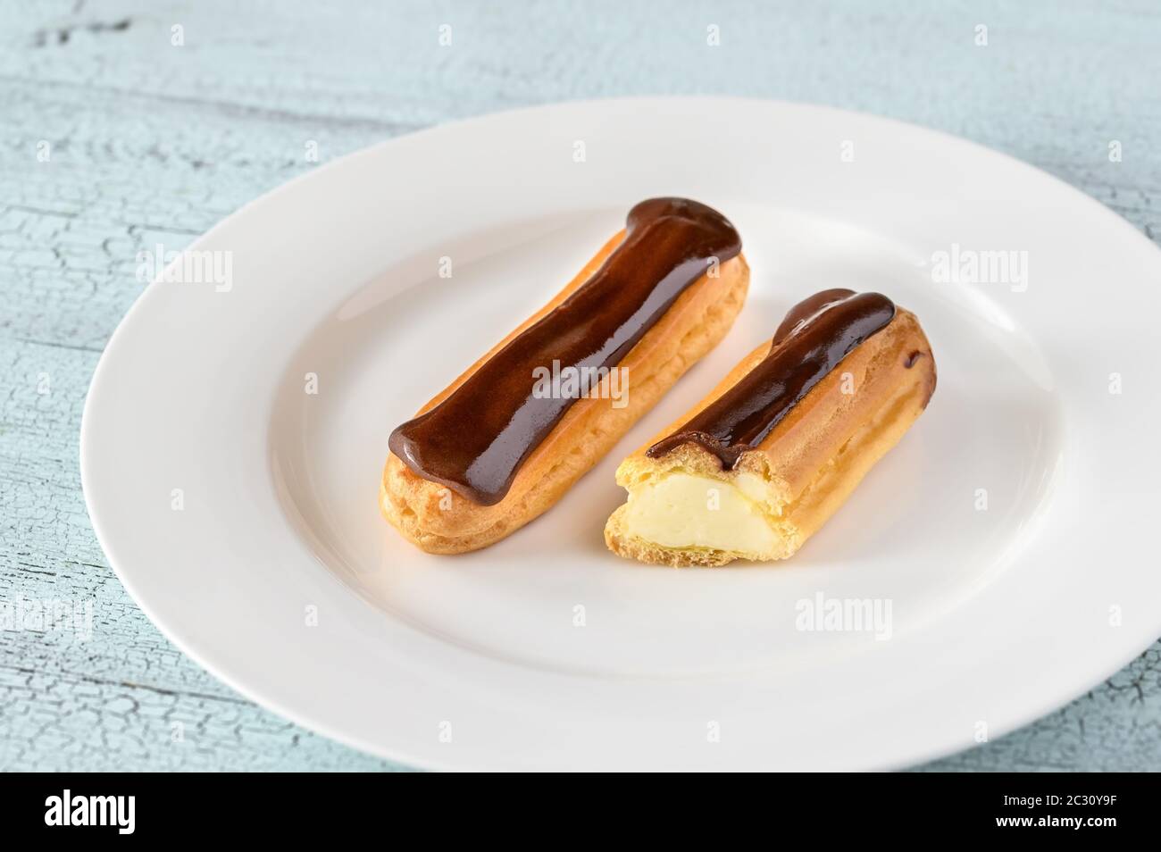Eclairs with chocolate topping on serving plate Stock Photo