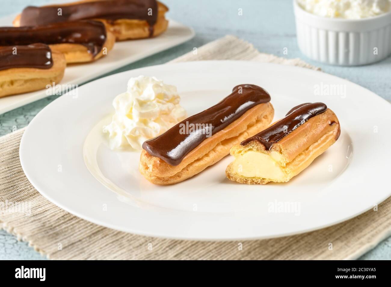 Eclairs with chocolate topping on serving plate Stock Photo