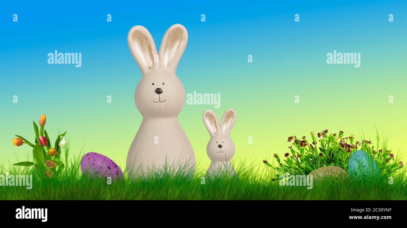 two easter bunnys stand on a meadow with easter eggs and flowes Stock Photo