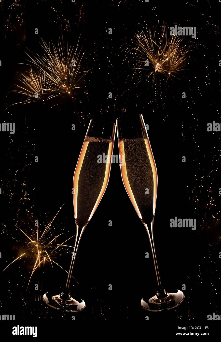 Champagne and golden fireworks on dark night sky at the turn of the year Stock Photo