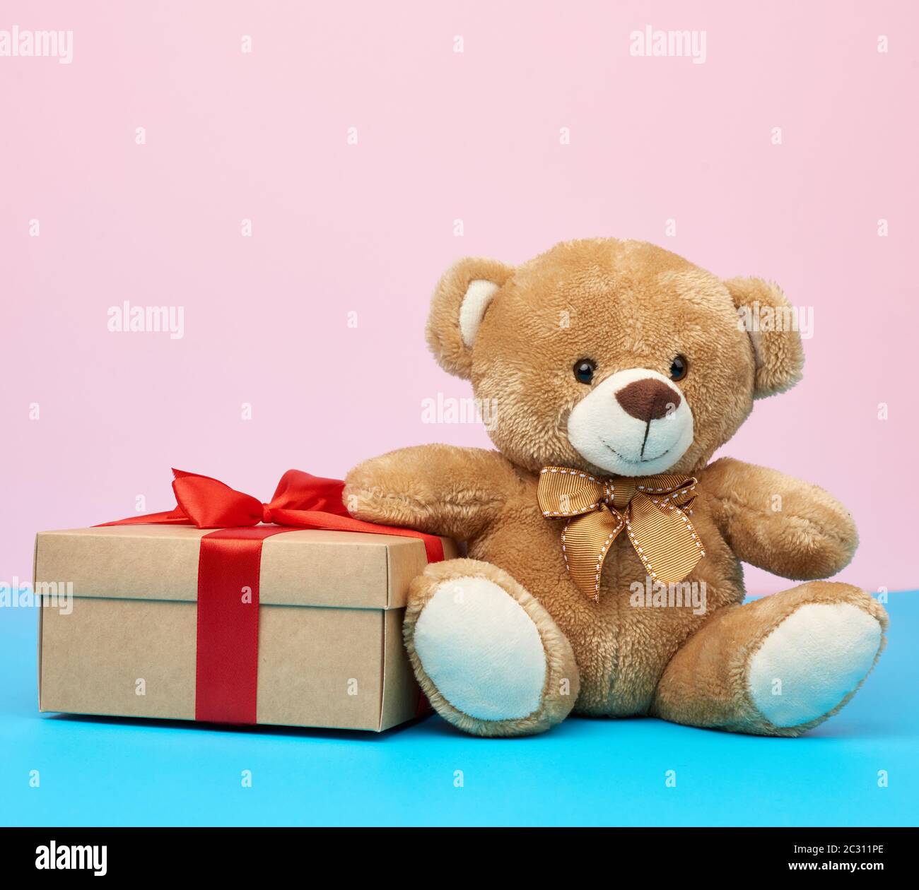 cute little brown teddy bear holds a brown box with a red ribbon on a ...