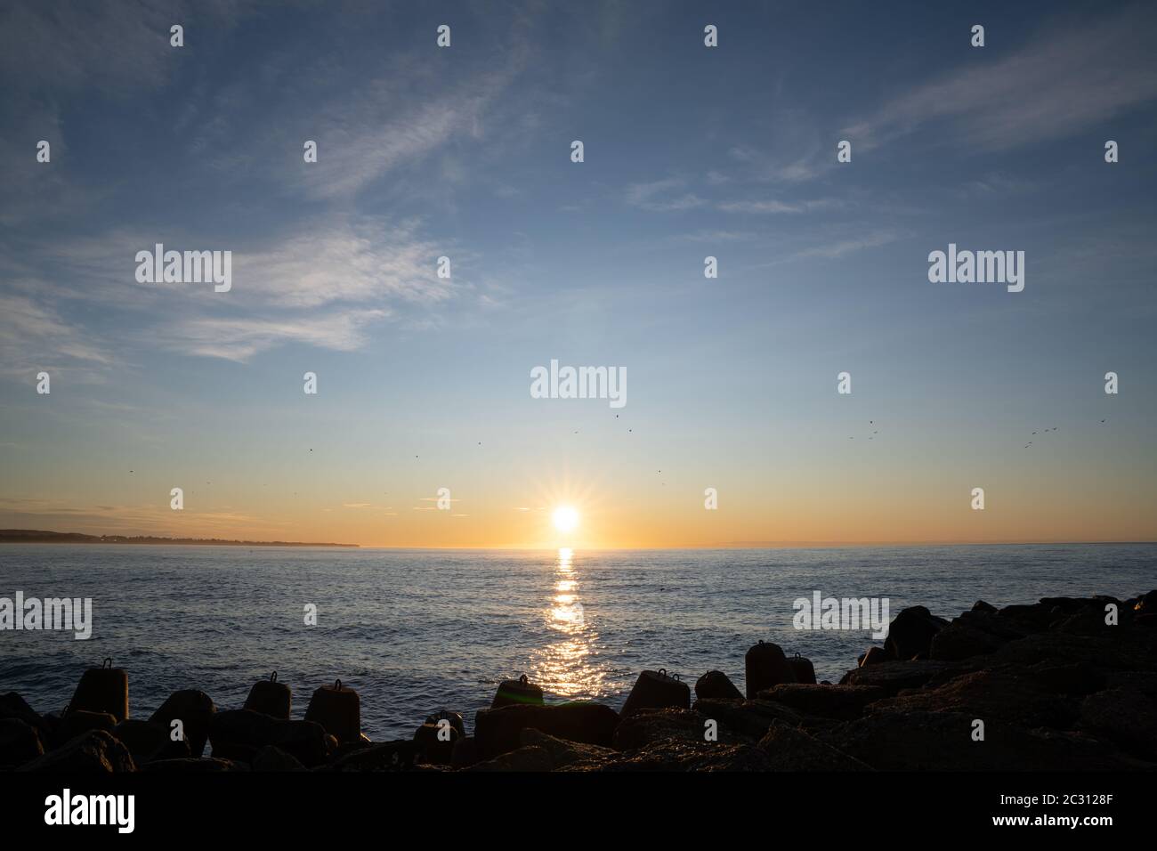 Beautiful view to rocky waterbreak in Oamaru, New Zealand with golden sunset. Stock Photo