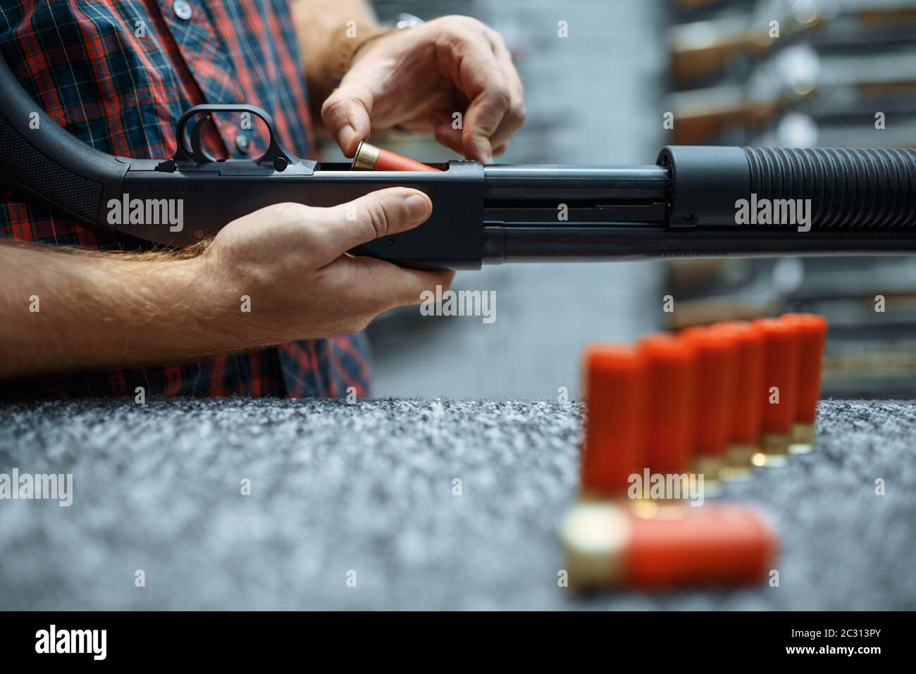 Male person with rifle loads ammo at showcase in gun shop. Euqipment ...