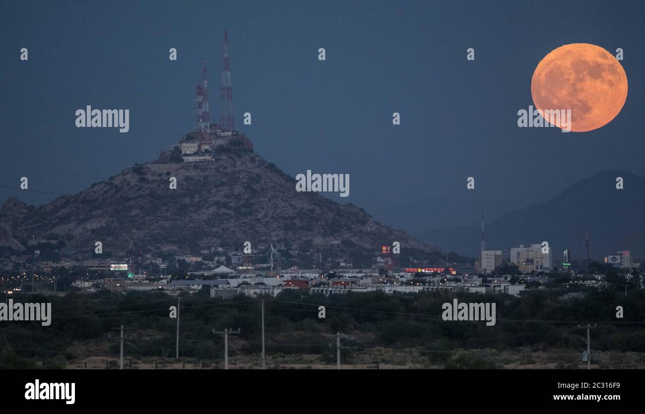 Espectacular vista de la Luna llena saliendo justo antes del anochecer, justo aun lado de el símbolo de Hermosillo, el cerro de la campana. Como cada Stock Photo