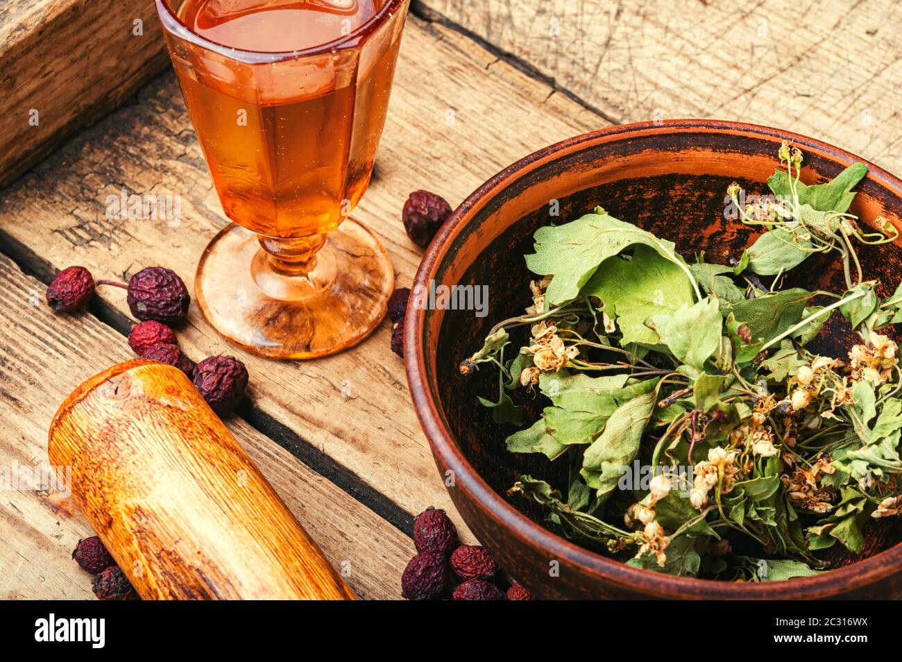 Dried hawthorn and berry leaves and a glass with healing tincture