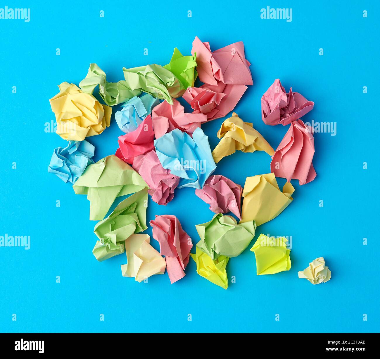 crumpled multi-colored paper stickers, top view, blue background, close up Stock Photo