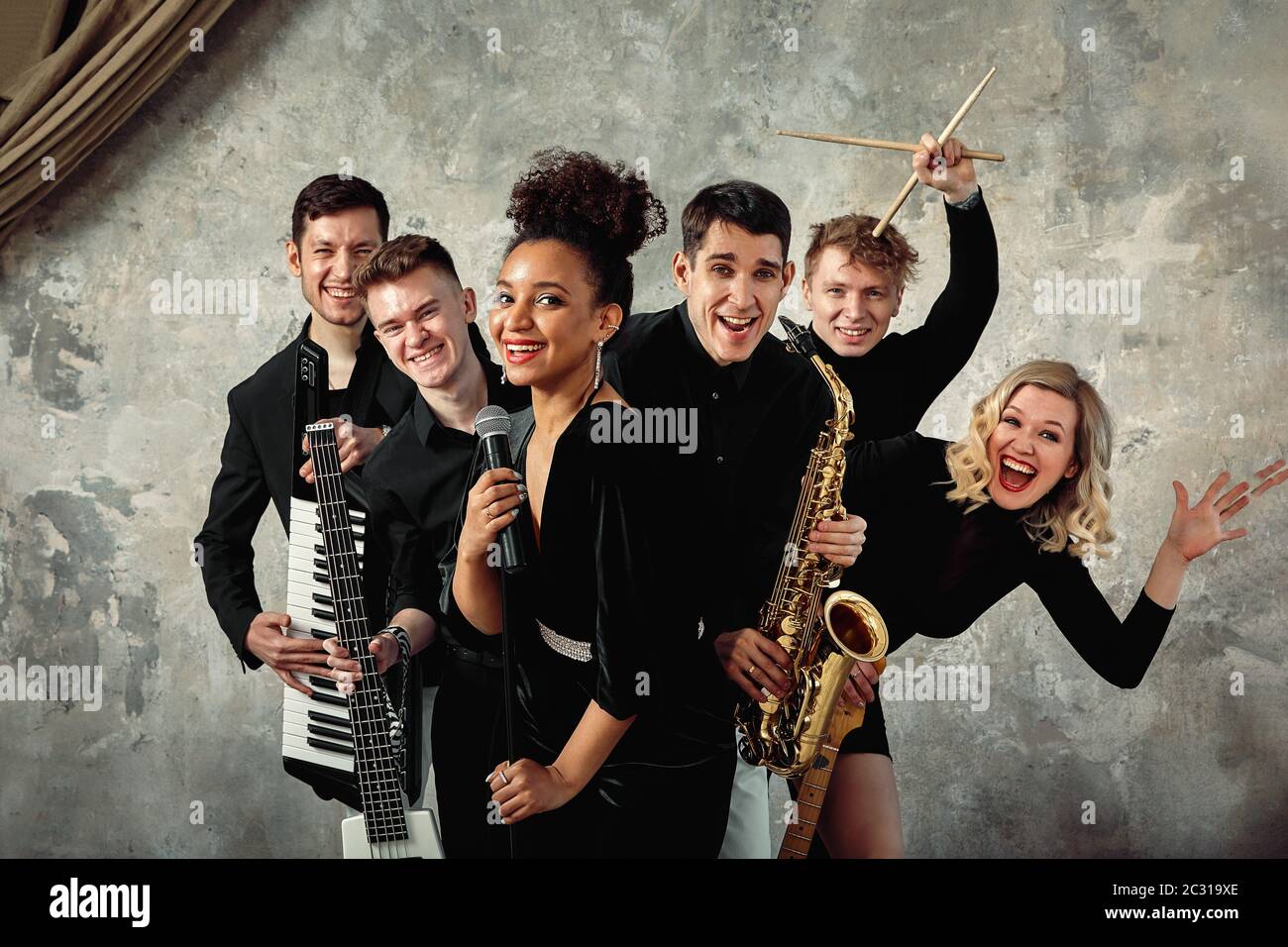 Cheerful international music group on a gray wall background, a group