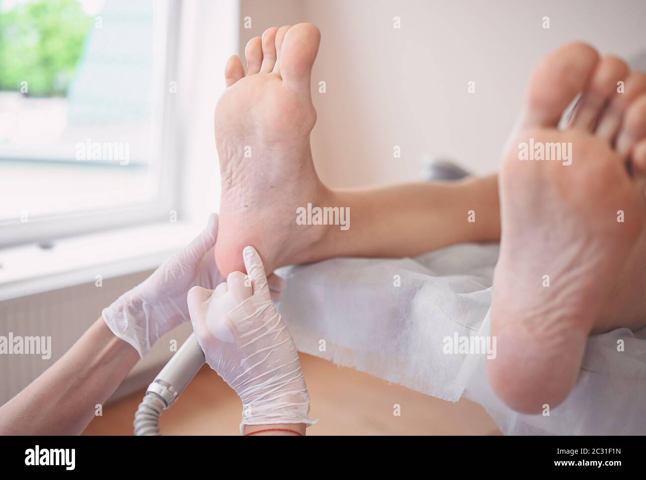 Podiatrist using grinding equipment and making procedure polish for feet  pedicure. Podology beautician in white gloves cleaning skin of client legs  Stock Photo - Alamy