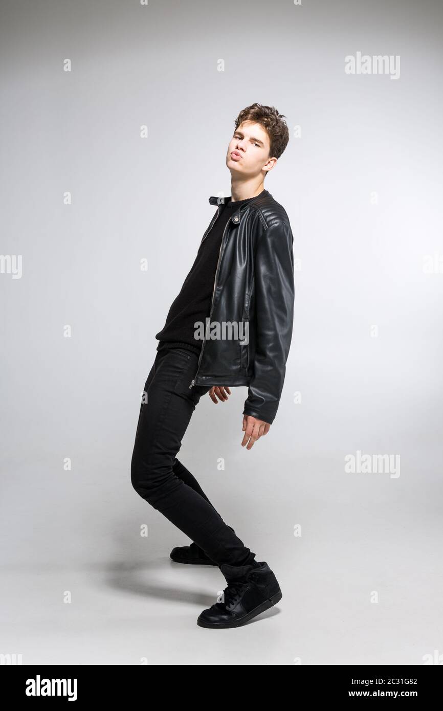 full length portrait of young fit man in dark cloths on the white background. Young Male Fashion Model Posing In Casual Outfit. Stock Photo