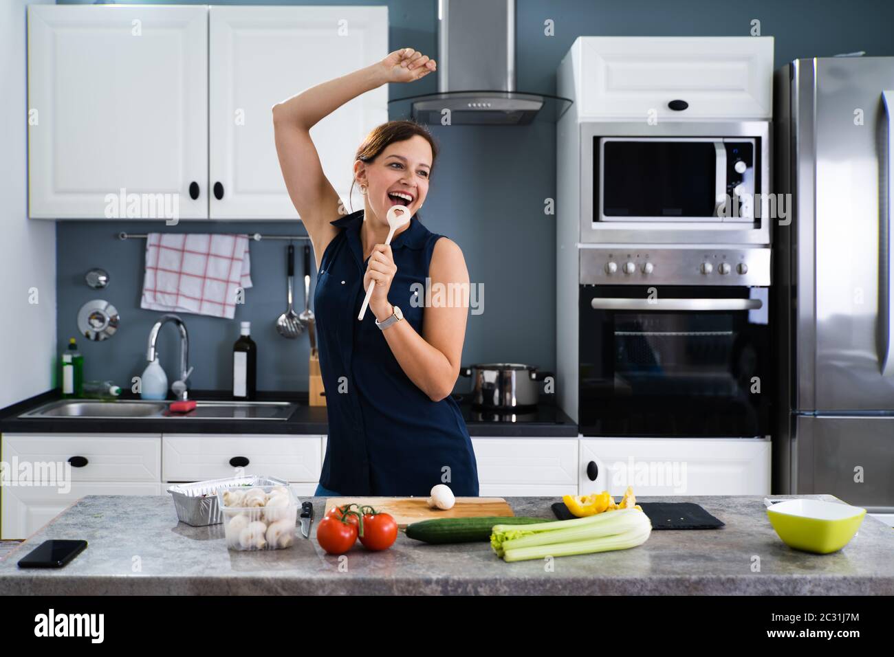 Funny young housewife cooking in kitchen Stock Photo - Alamy