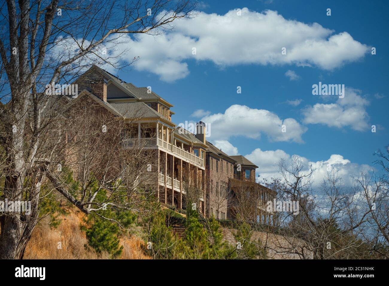 Two large brick homes with verandas on a hilltop under clear blue skies Stock Photo