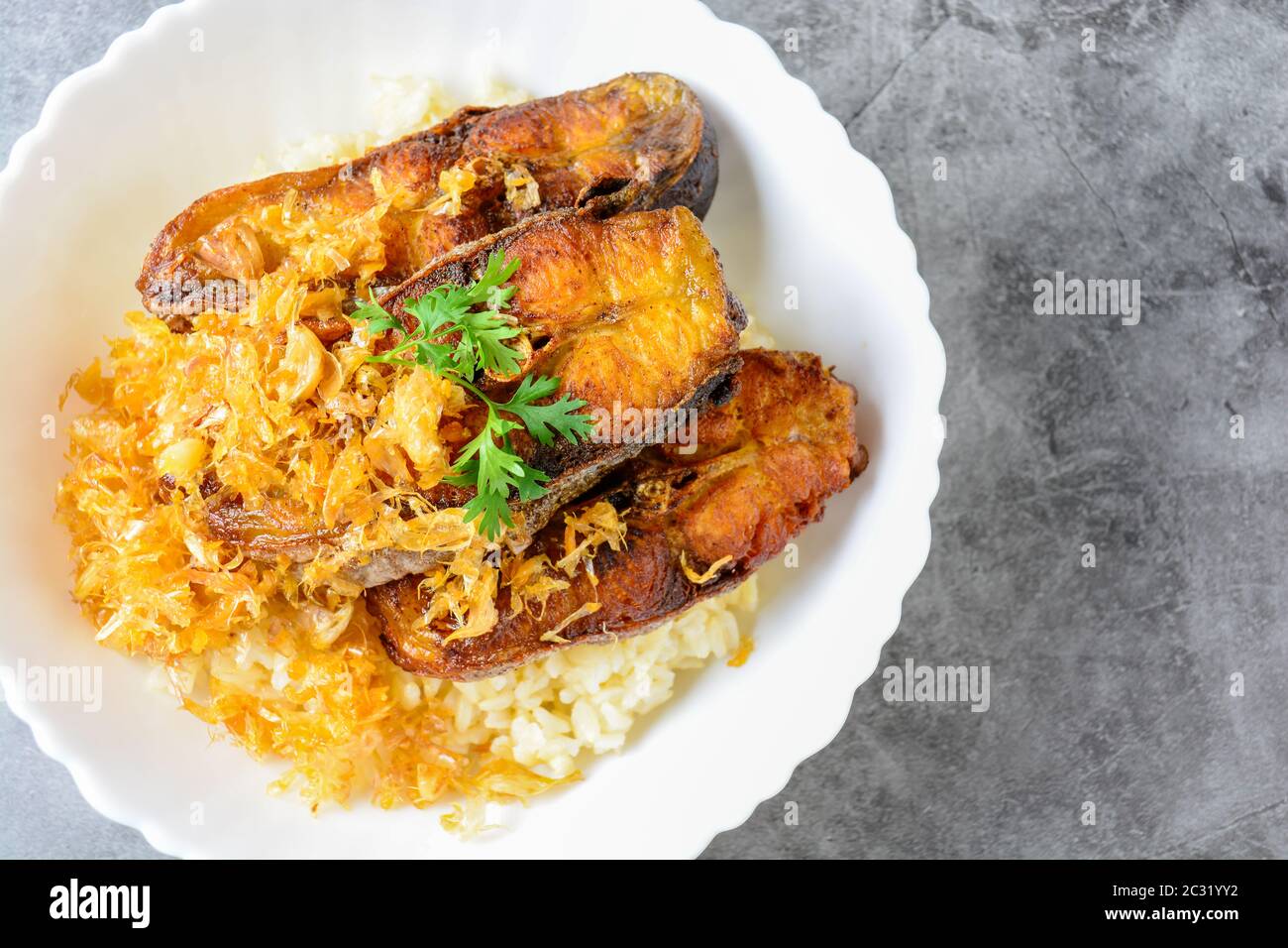 Deep fried sliced Pangasius fish with garlic, served with brown rice. Stock Photo