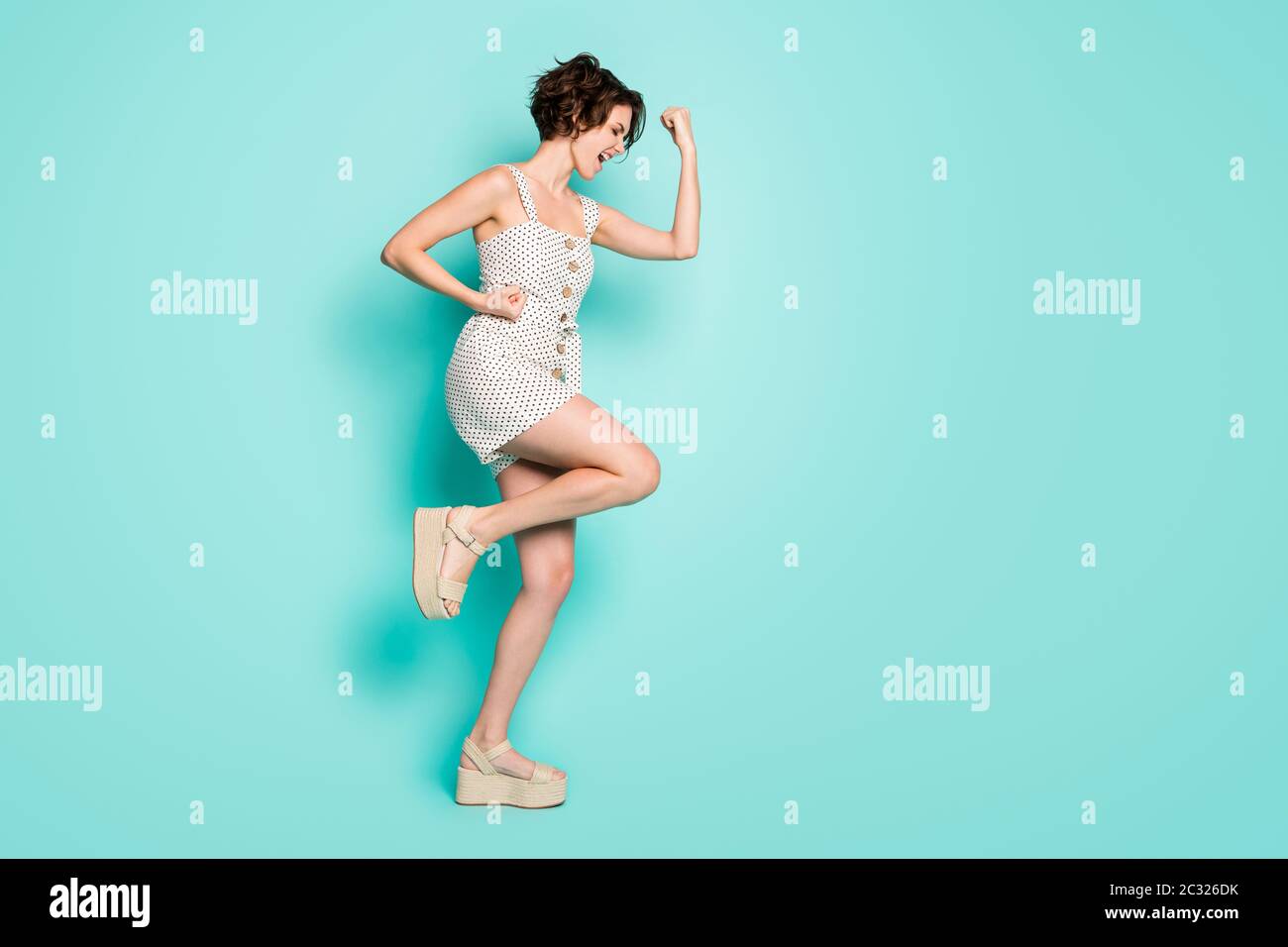 Full size profile photo of cool cheerful lady raise fists hands celebrate lottery winning wear casual summer dotted overall open toe shoes isolated Stock Photo