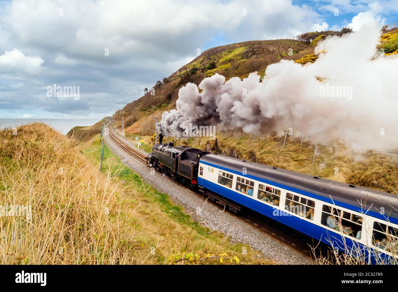 Steam train with passenger carriages on coastal railway Stock Photo