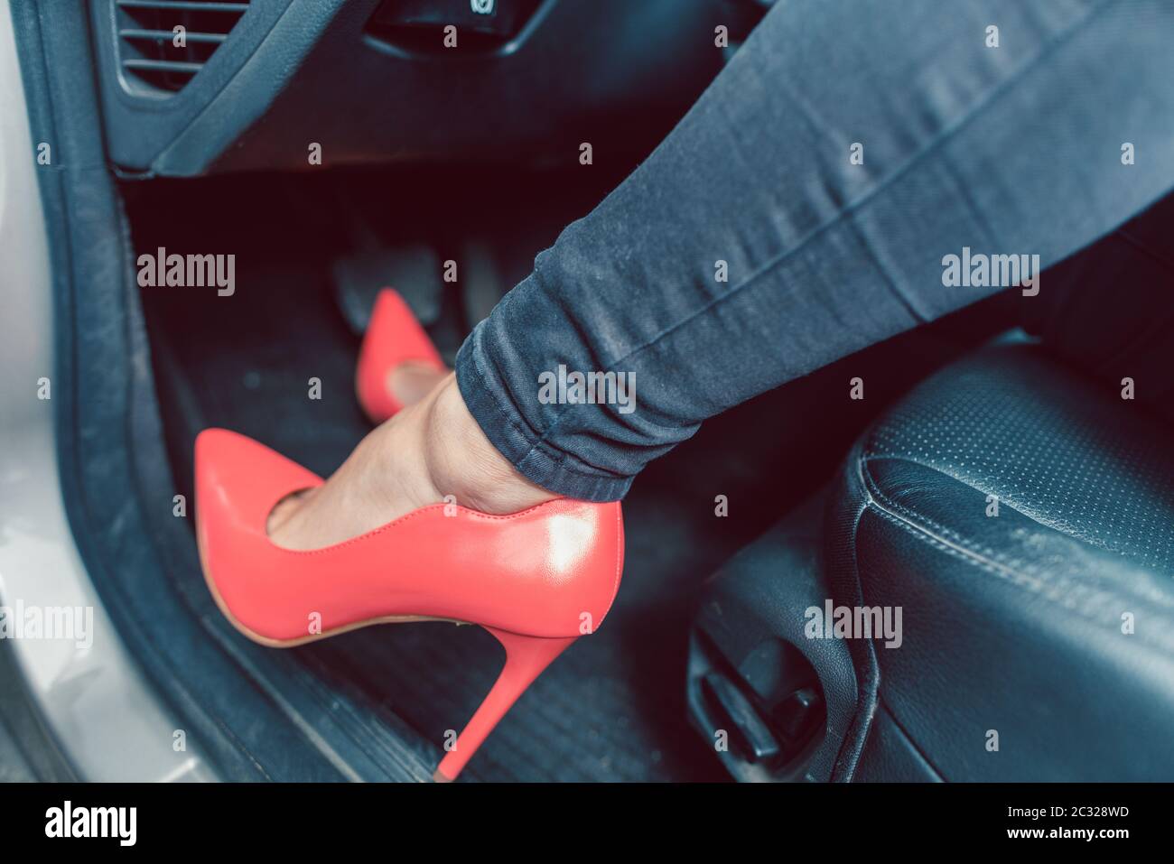 Woman driving a car in an unsafe manner with red high-heel shoes Stock Photo