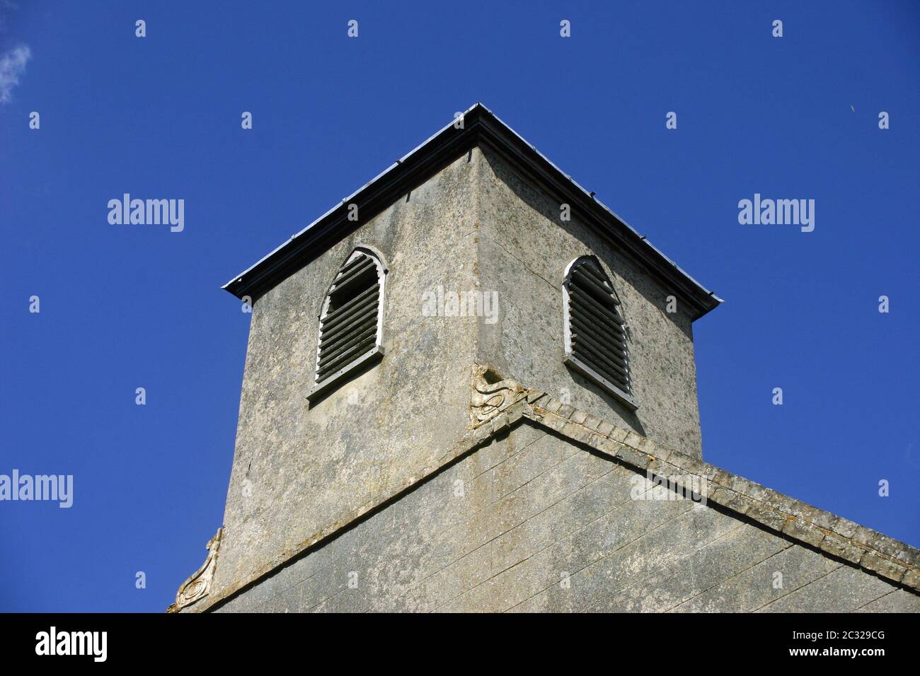 King Charles the Martyr church in Shelland, Suffolk. Bell tower viewed from the south-western corner. Mown grass in the foreground. Trees and blue sky Stock Photo