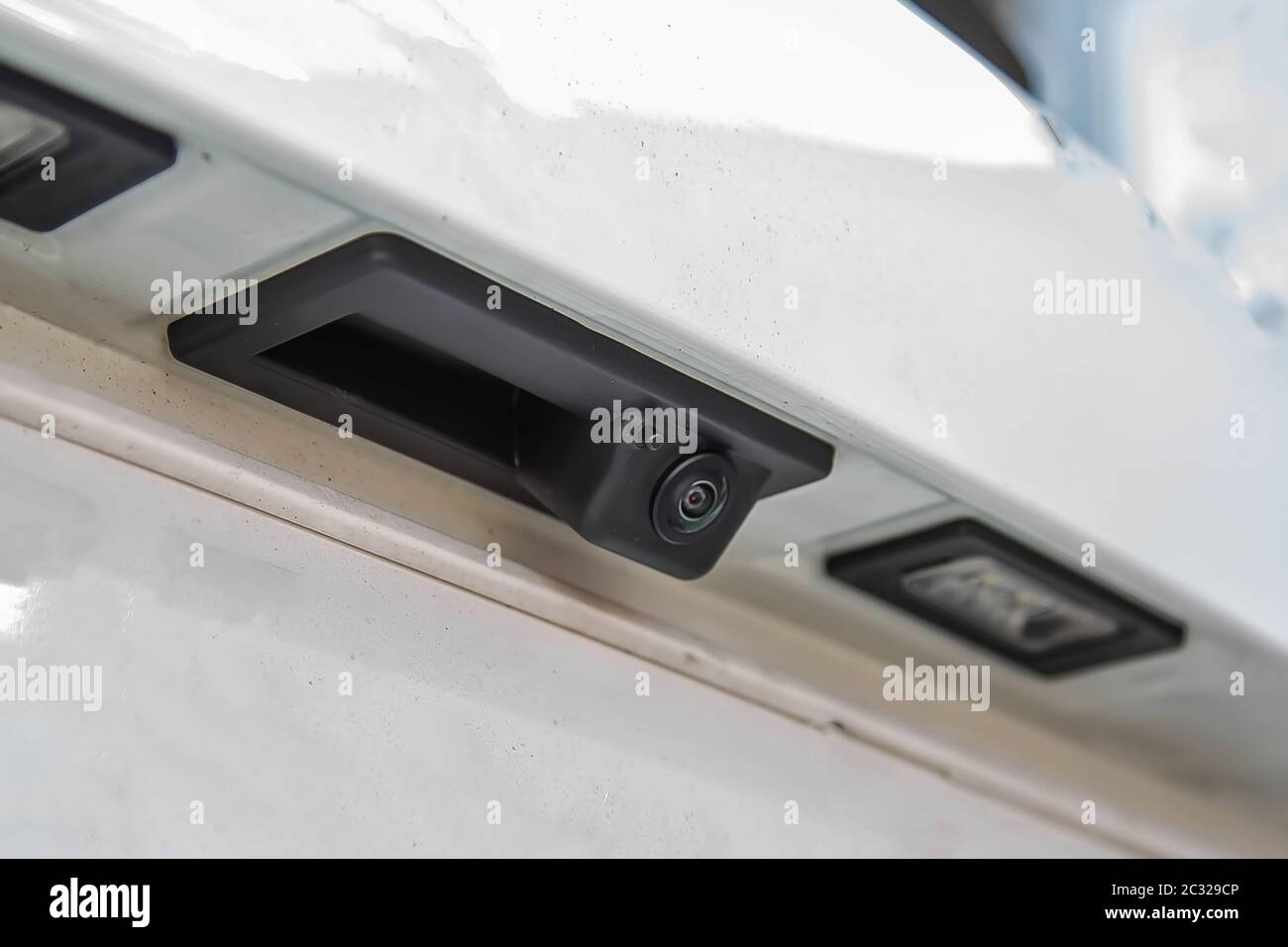 Black rear view camera with washer, car exterior. On white suv, license