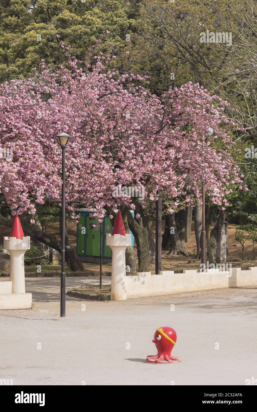 Funny red octopus sculpture  with the pink cherry blossom of Asukayama park in the Kita district Stock Photo