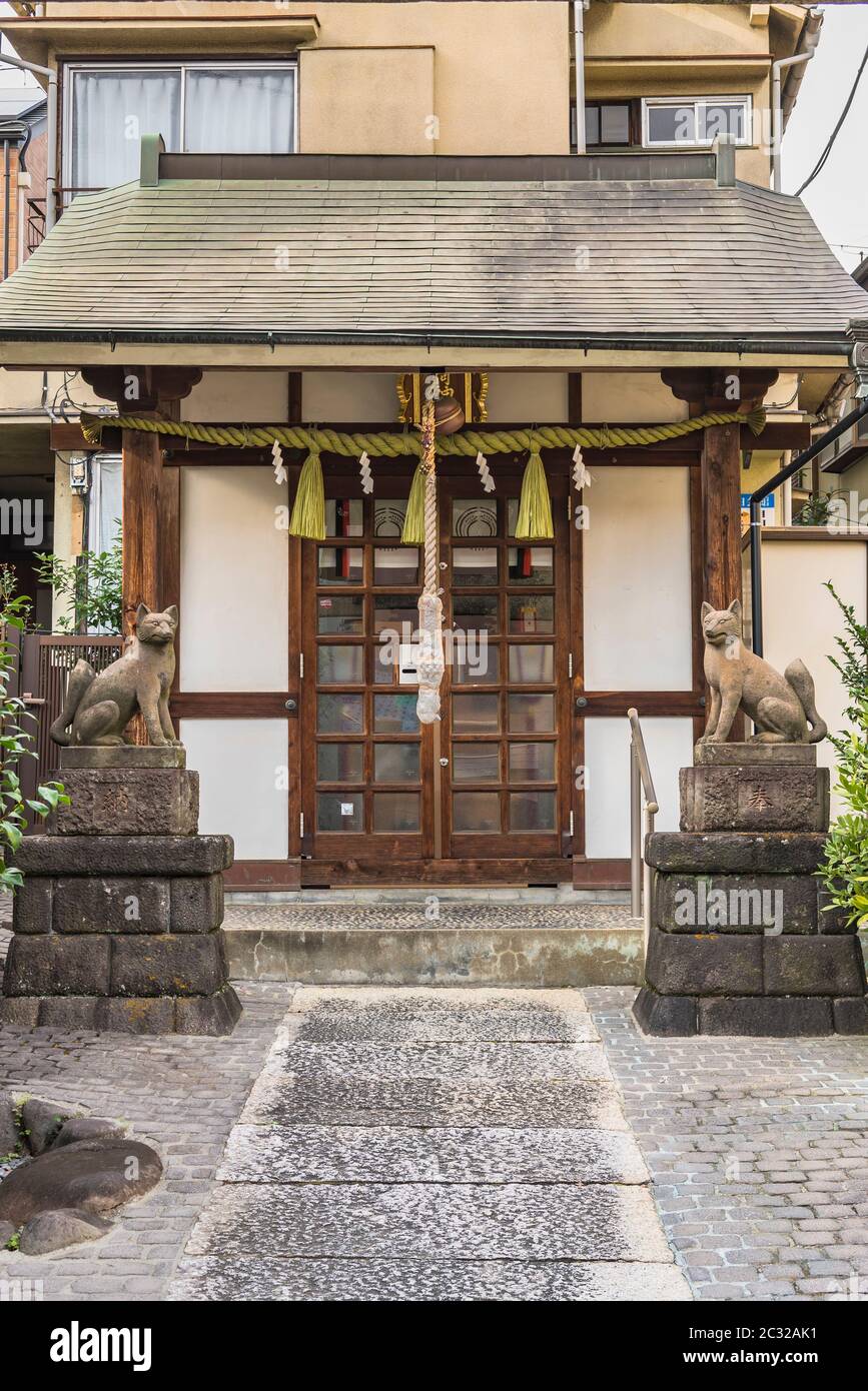 Two statues of foxes inari, deity of rice in the Shinto shrine of Mejiro Toyosaka Inari Jinja in Tokyo. Stock Photo