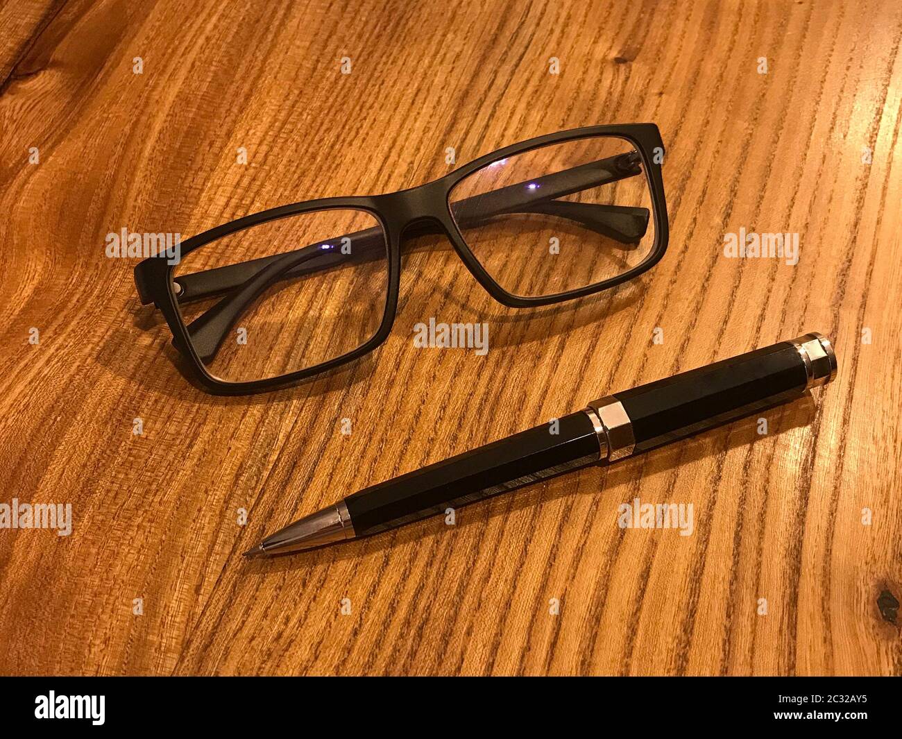 Glasses and pen on wooden desk. Business, education Stock Photo