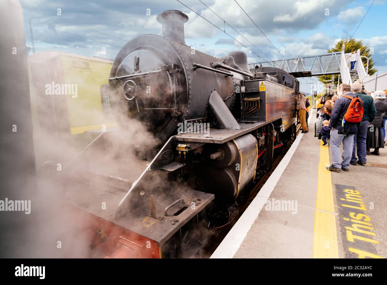 Passengers waiting for old vintage steam train or locomotive at station ...