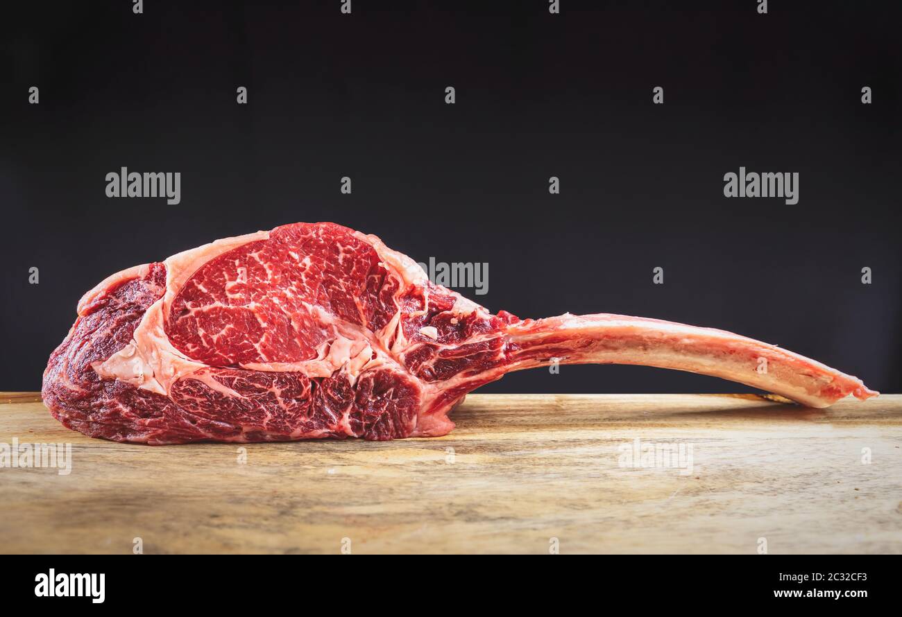 Dry aged wagyu tomahawk steak on a wooden cutting board Stock Photo