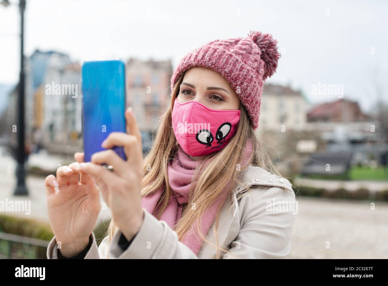 Woman wearing corona mask making selfie with phone in city Stock Photo