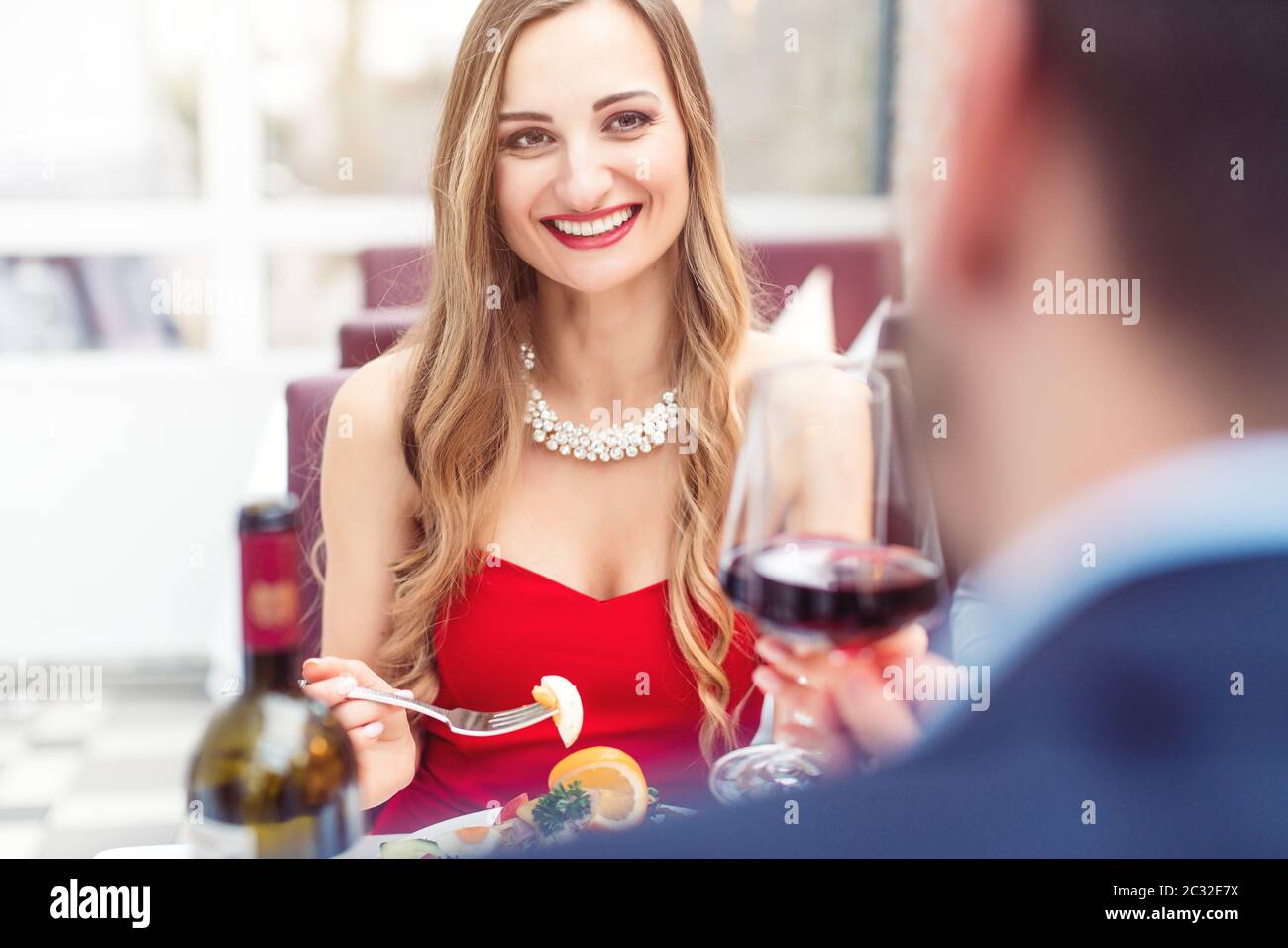 Couple toasting with red wine in romantic restaurant looking at each other Stock Photo