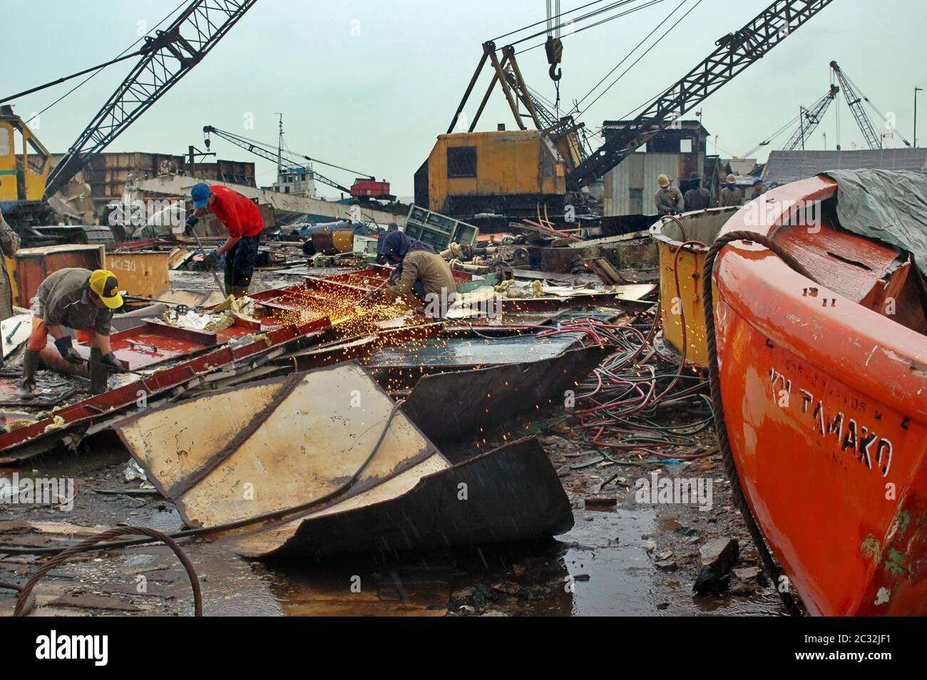 Men working on a rainy day at a shipbreaking yard in Jakarta, Indonesia. Stock Photo