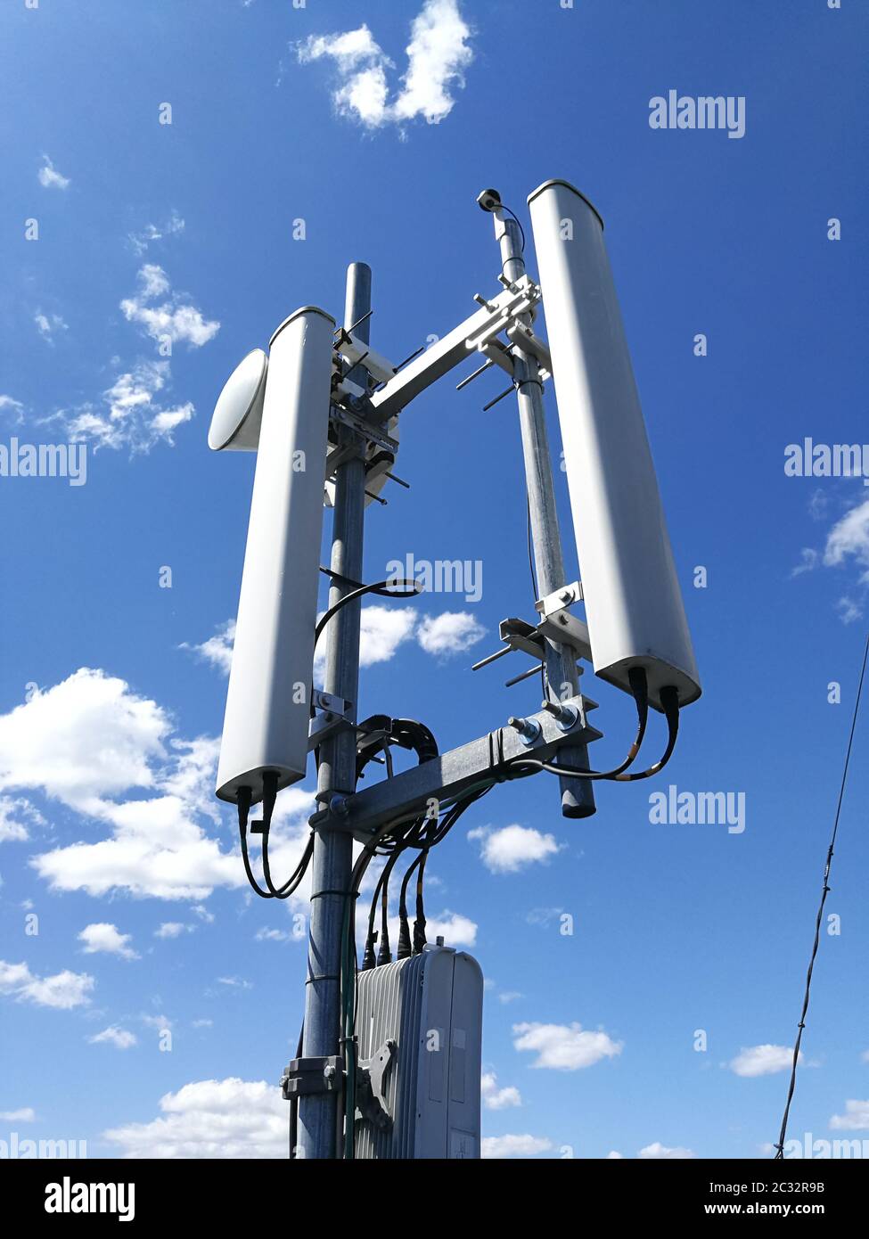 GSM (Global System for Mobile communication) base station and repeater  tower in front of blue cloudy sky for telecommunications Stock Photo - Alamy