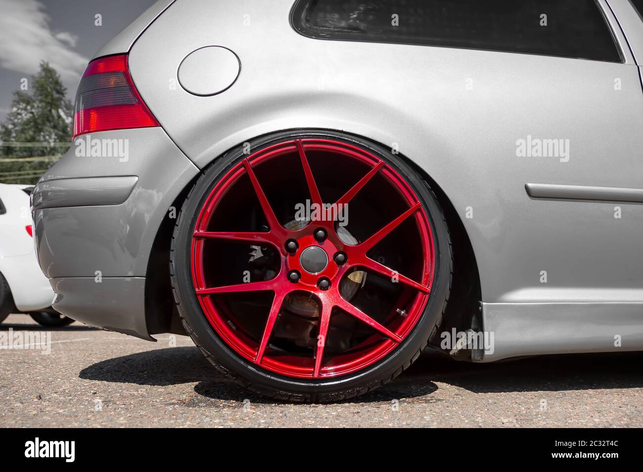 red candy colored light alloy wheels on silver hatchback Stock Photo - Alamy