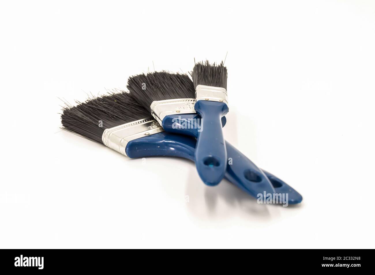 Three paint brushes with blue colored handles on an isolated white