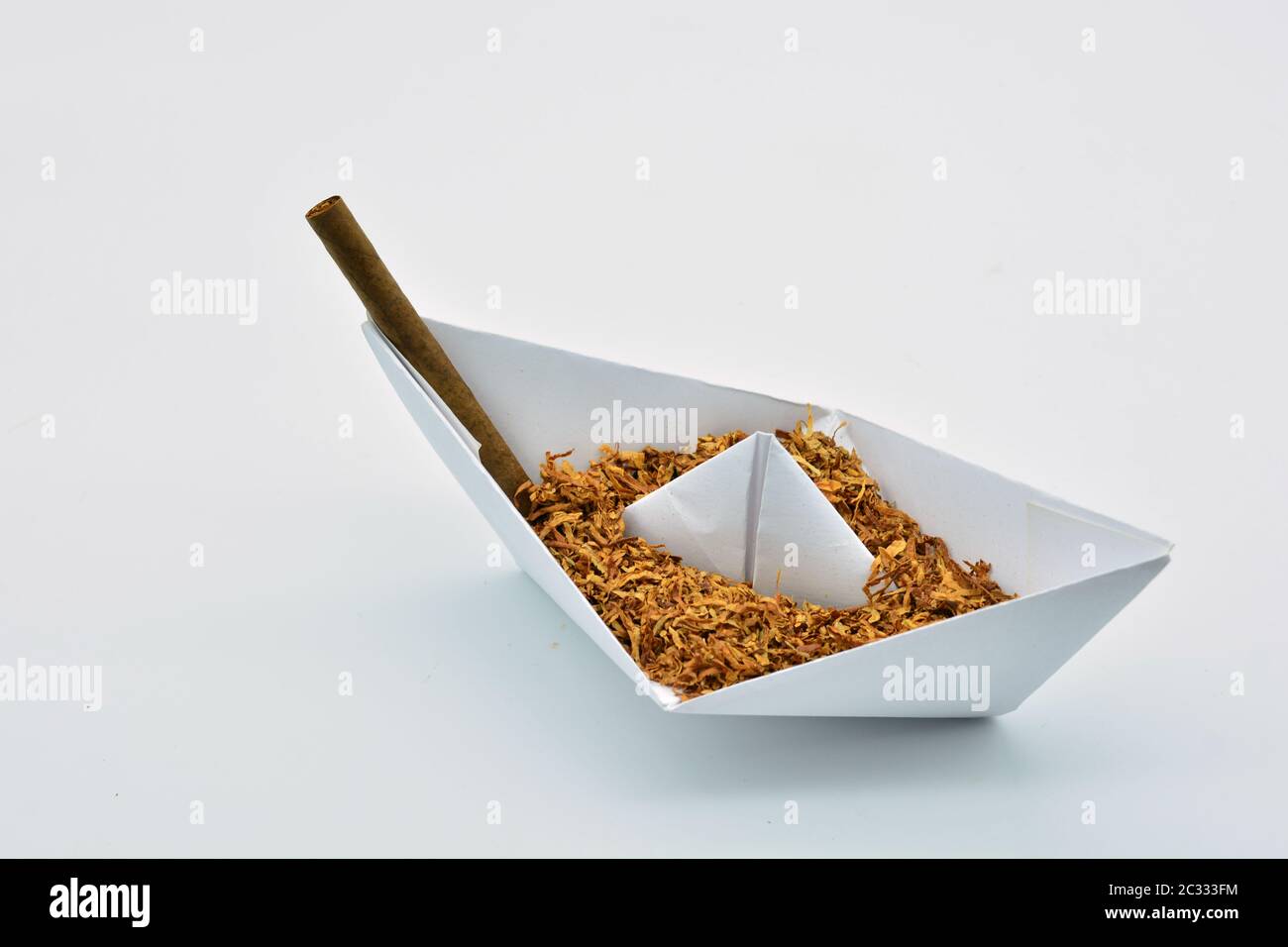 Barco de papel cargado de tabaco sobre fondo blanco Stock Photo