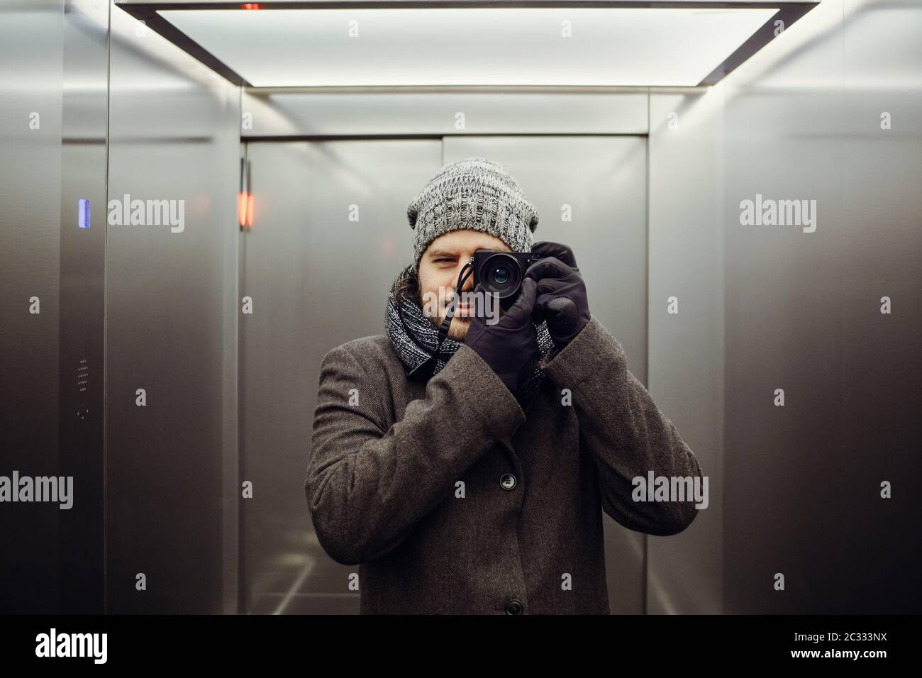 Male photographer taking a self picture in an elevator. Mirror selfie portrait, learning photography and analog film look concep Stock Photo