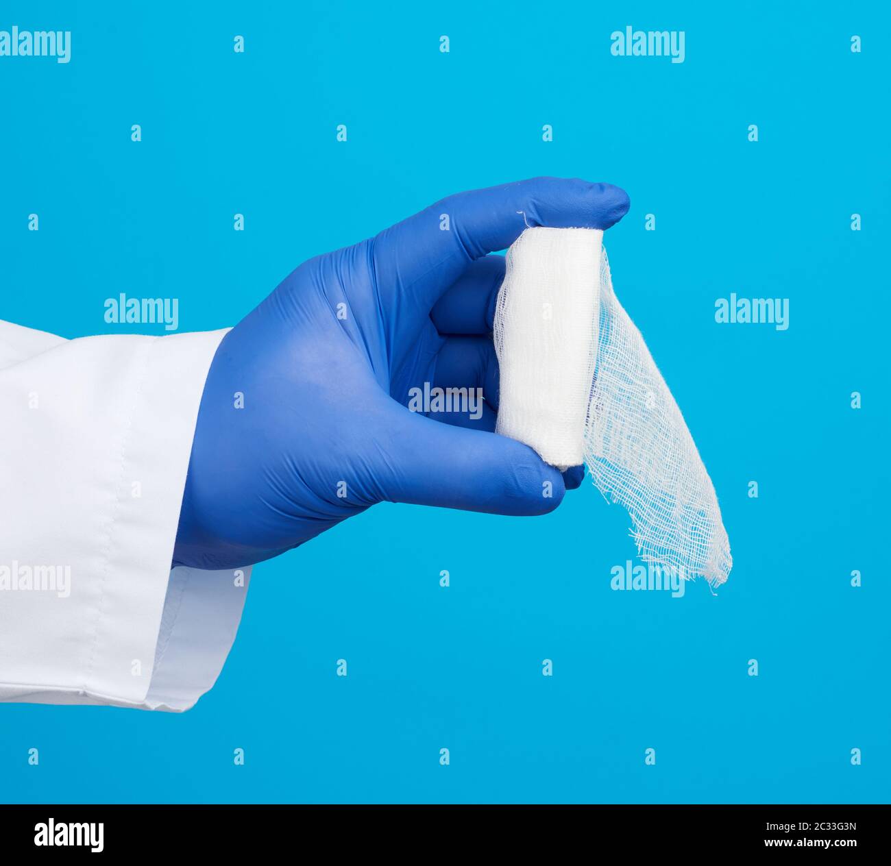 male hand in blue sterile gloves holds a white twisted gauze medical bandage on a blue