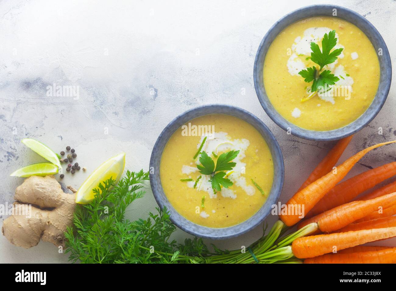 Two Bowls Of Carrot Soup With Ingredients Stock Photo