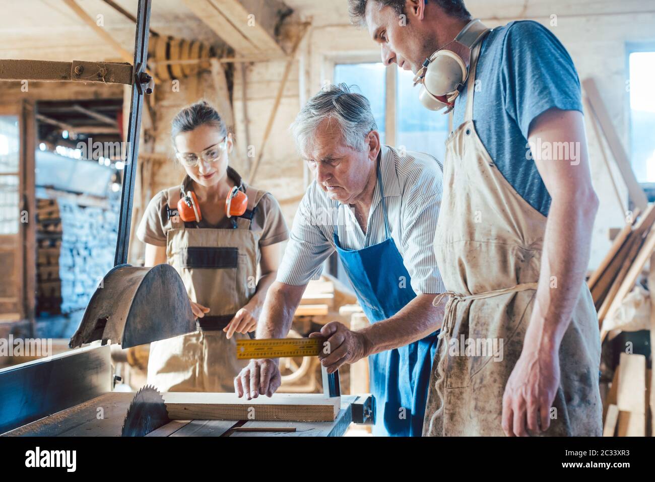 Experienced master carpenter transferring knowledge to his younger colleagues Stock Photo