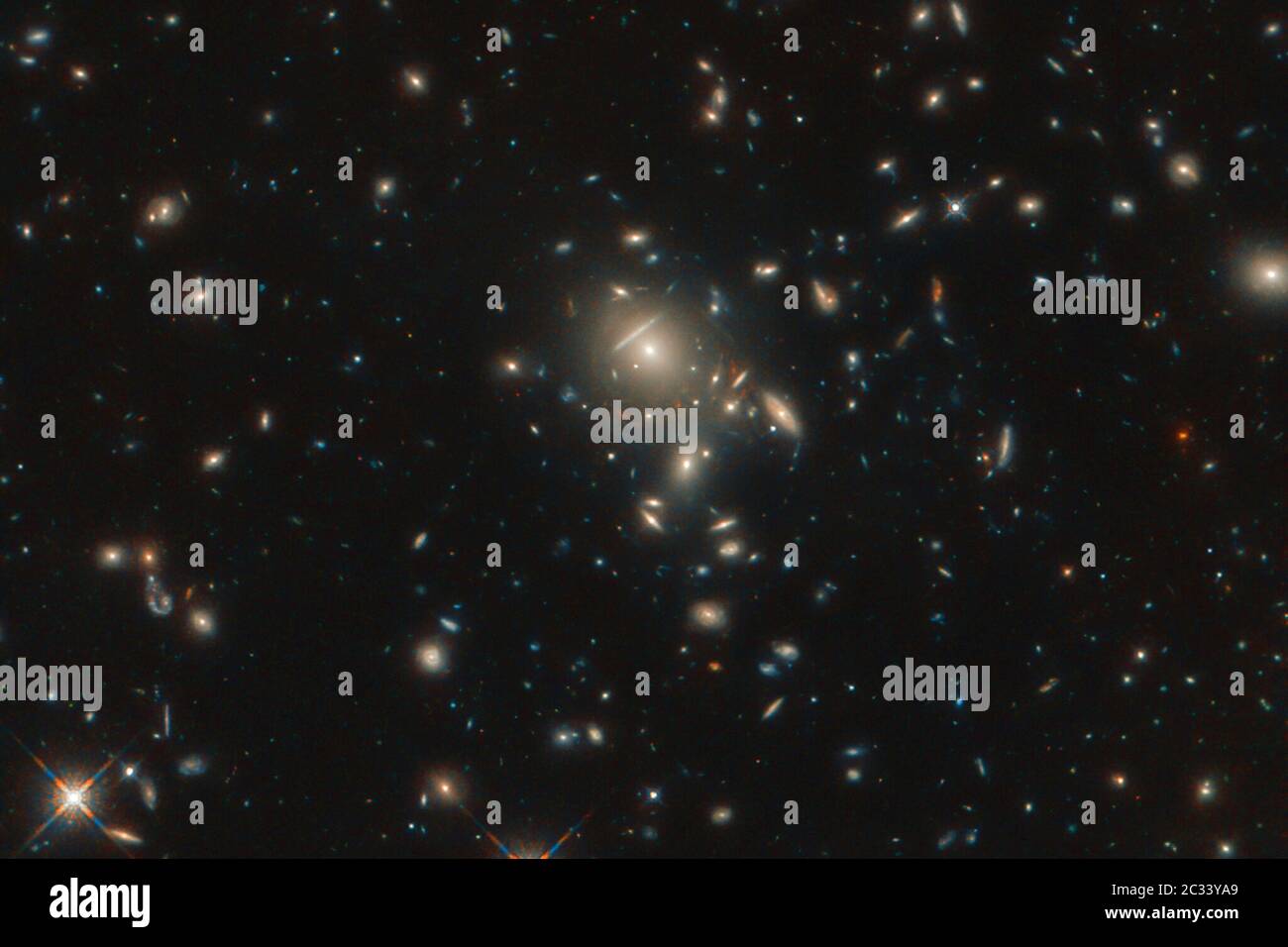 Seen in incredible detail, thanks to the NASA/ESA Hubble Space Telescope, is the starburst galaxy formally known as PLCK G045.1 61.1. The galaxy appears as multiple reddish dots near the center of the image and is being gravitationally lensed by a cluster of closer galaxies that are also visible in this image. Gravitational lensing occurs when a large distribution of matter, such as a galaxy cluster, sits between Earth and a distant light source. Credit: UPI/Alamy Live News Stock Photo
