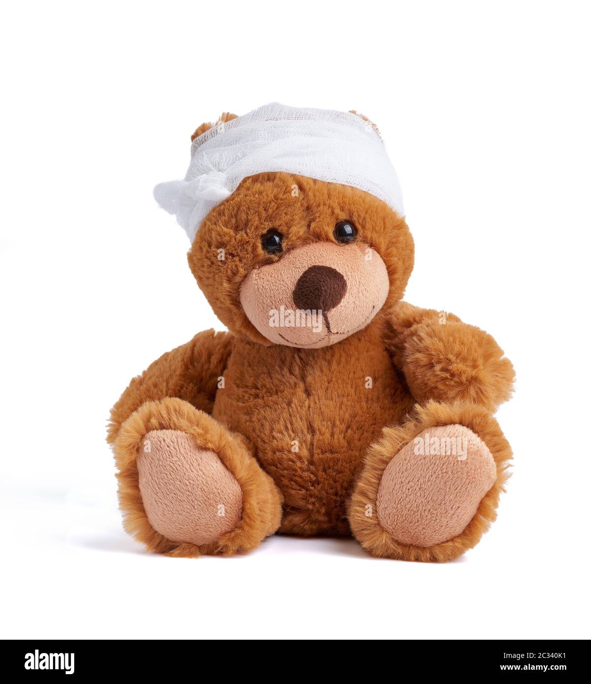 brown teddy bear with a bandaged head in a white medical bandage on a white background, concept of child trauma, headache Stock Photo