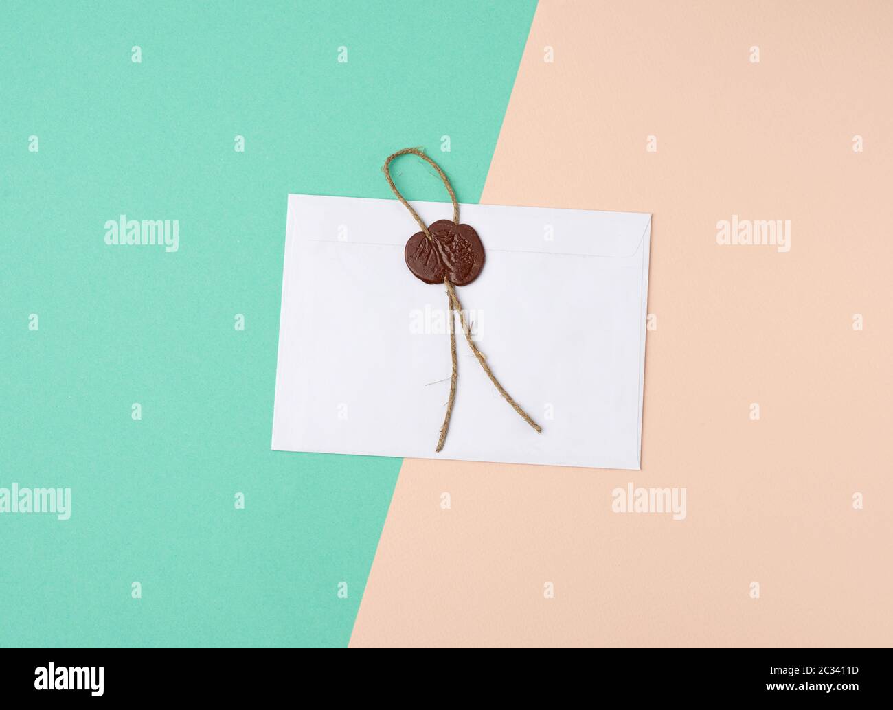 rectangular white paper envelope and brown stamp, color background, flat lay Stock Photo