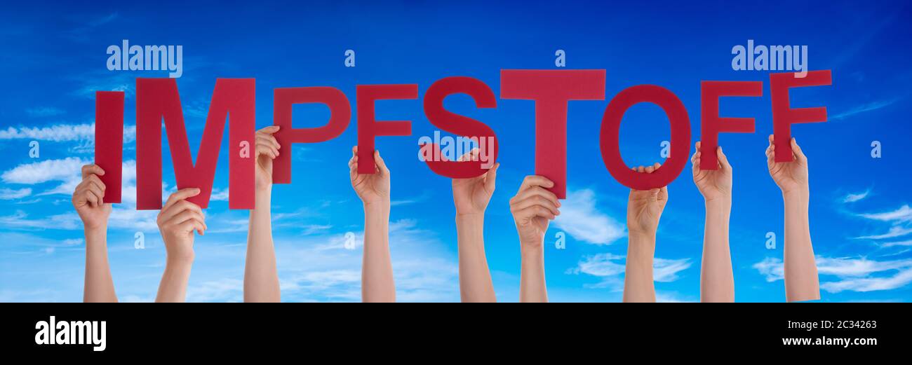 People Hands Holding Colorful German Word Impfstoff Means Vaccine. Blue Sky As Background Stock Photo