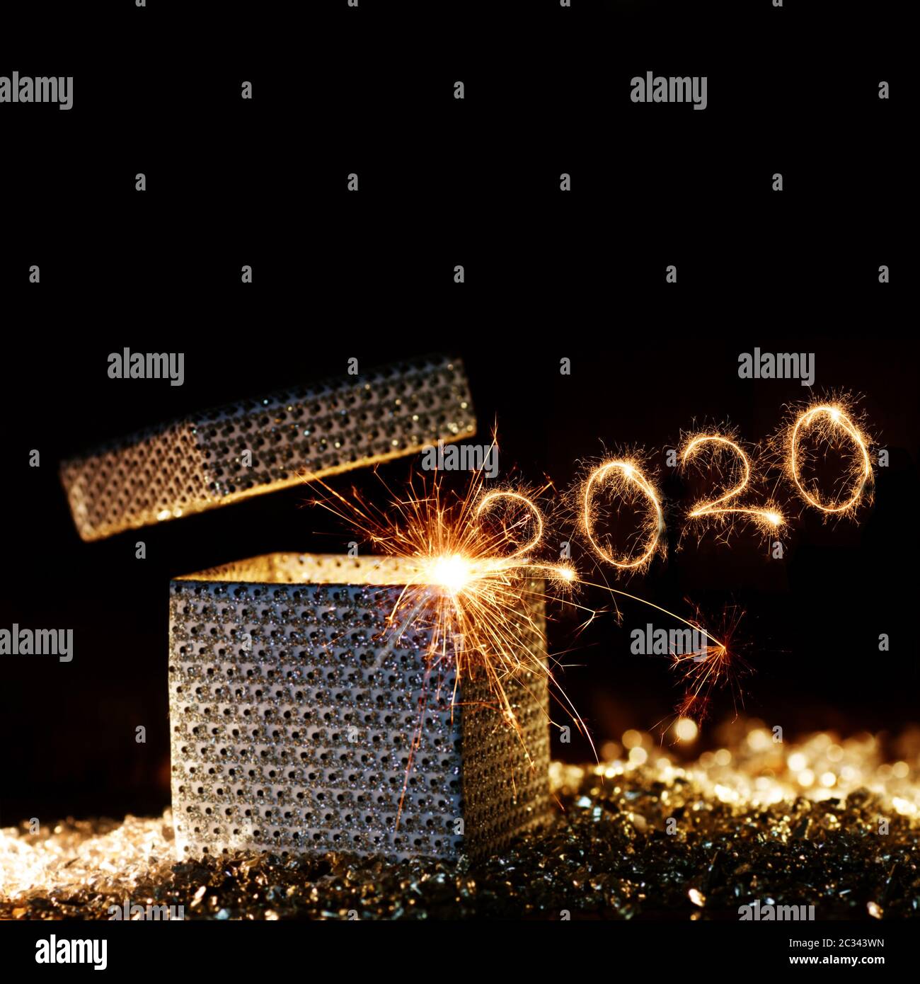 Magical sparkling golden new years surprise package 2020 in front of black background for a luxury concept Stock Photo