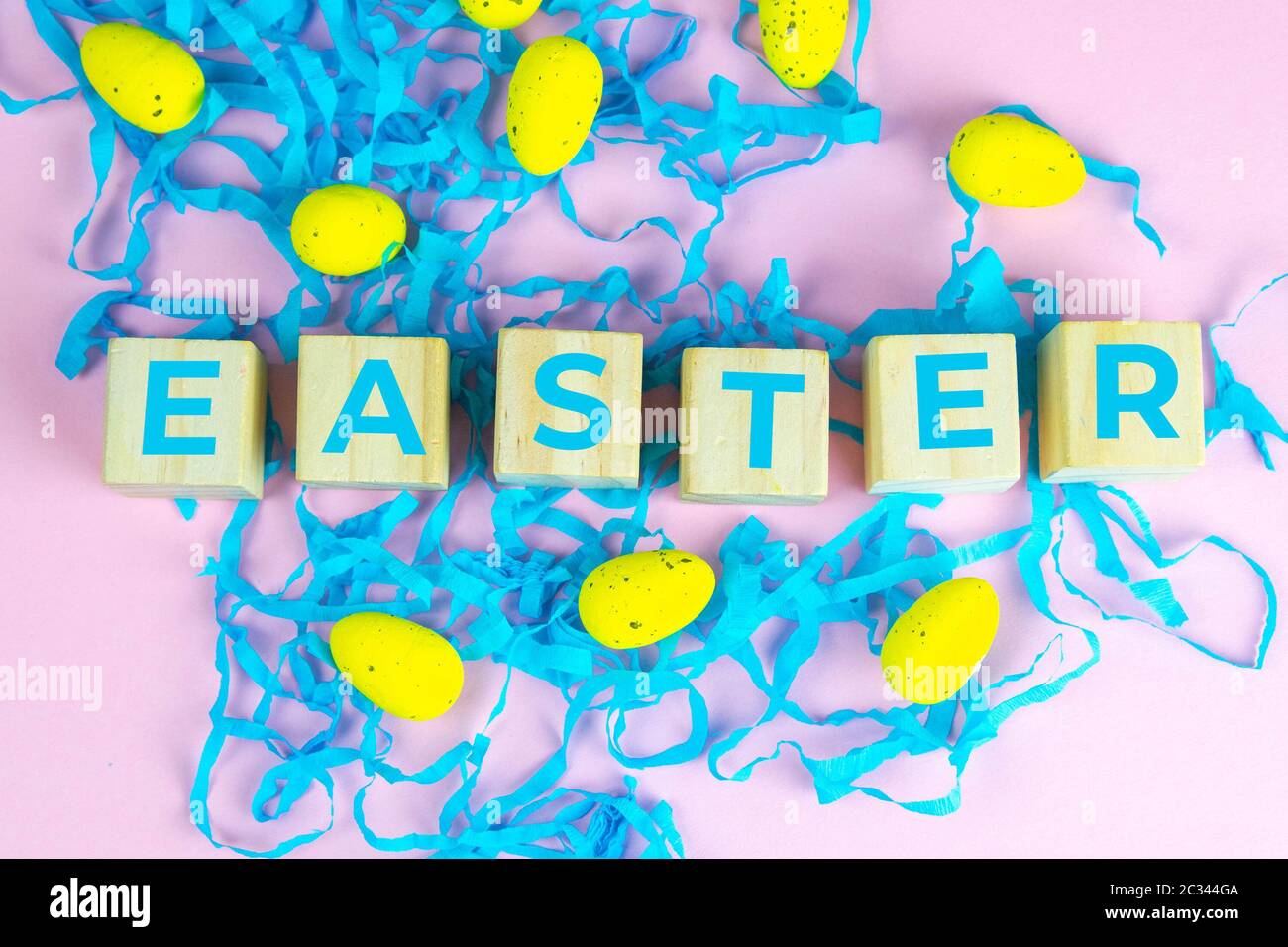 Word Easter on wooden cubes and surrounded with multiple egg decorations as a festive Easter background composition. Stock Photo